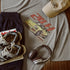 T-shirt with car graphic, cap, sneakers, and headphones on a wooden surface